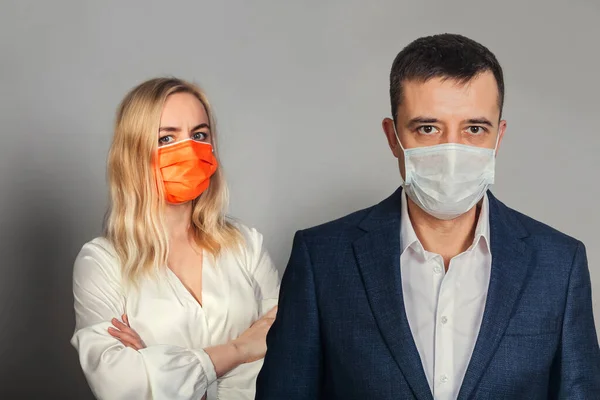 A woman and a man with an anxious faces in a medical mask. Office employees in quarantine