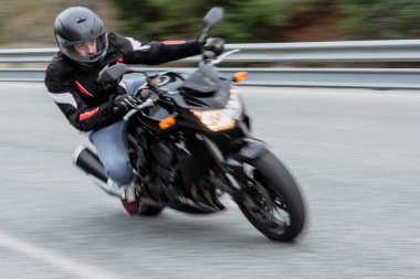 Biker driving his black motorbike by road