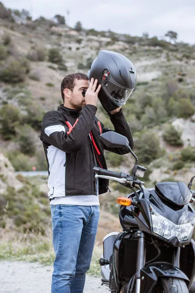 Pengendara sepeda motor laki-laki muda mengenakan helm untuk mengendarai sepeda motornya — Stok Foto