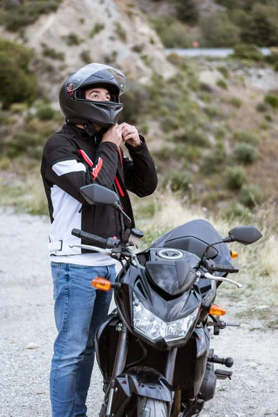 Pengendara sepeda motor laki-laki muda mengenakan helm untuk mengendarai sepeda motornya — Stok Foto