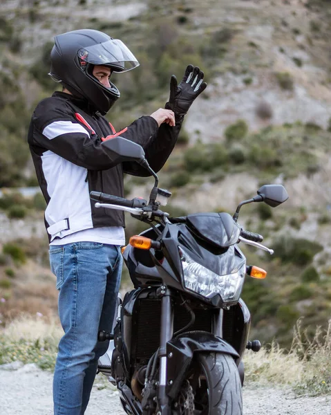 Pengendara motor muda memakai sarung tangan sebelum mengendarai sepeda motornya . — Stok Foto