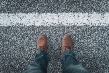 Men's boots and legs on the road across the line. Concept of exploration and adventures.