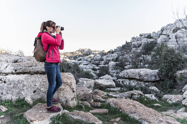 Young woman explorer photographing in the mountain. Concept of adventure, excursion and trips.