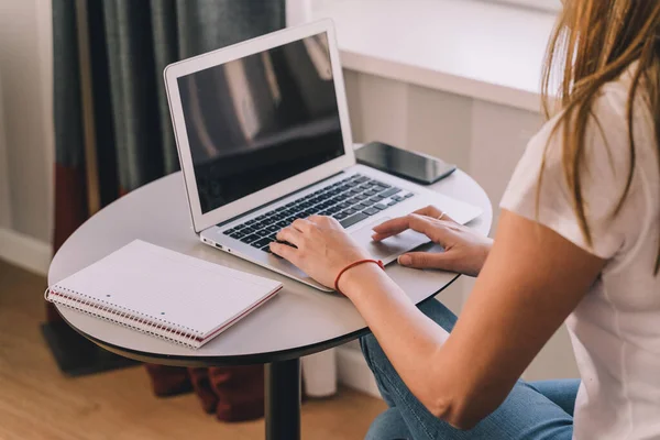 Genç bir kadın laptopuyla evde çalışıyor ya da ders çalışıyor. Ağlar ve yeni teknolojiler kavramı.