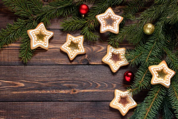 Quadro feito de ramos de abeto e biscoitos caseiros e brinquedos de Natal, em uma superfície marrom de madeira . — Fotografia de Stock