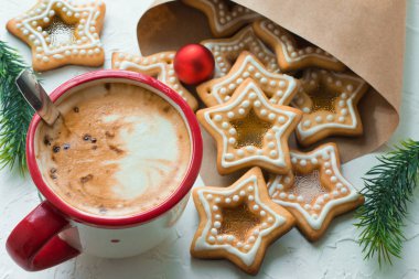 Beyaz masa üzerinde kahve fincanı ev yapımı Noel yıldızı şekerlemeli kurabiyeler içinde Noel ağacı dalları ve Noel ağacı topları olan kağıt bir paket.