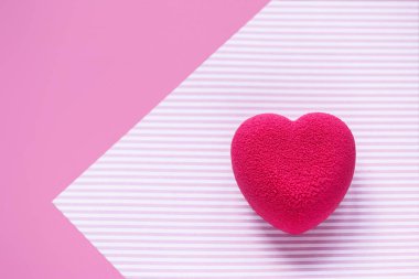 Sevgililer Günü konsepti. Pembe çizgili yüzeyde pembe kadife kalp şeklinde bir pasta.. 