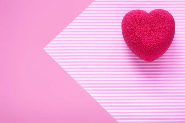 Concepto de San Valentín. Pastel en forma de corazón de terciopelo rosa sobre una superficie de rayas rosadas . — Foto de Stock