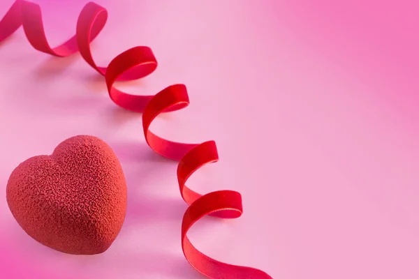 Concepto de San Valentín. Pastel en forma de corazón de terciopelo rojo sobre fondo rosa con cinta de terciopelo rojo — Foto de Stock