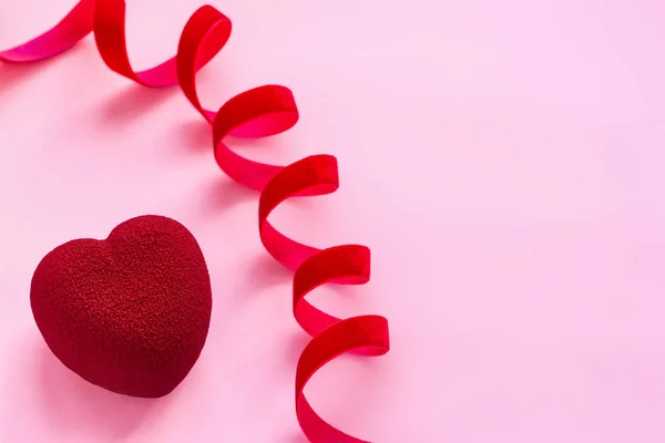 Concepto de San Valentín. Pastel en forma de corazón de terciopelo rojo en superficie rosa con cinta de terciopelo rojo — Foto de Stock
