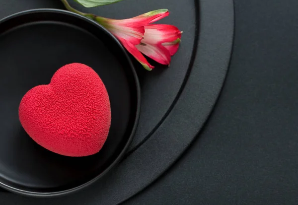 Valentines day concept. Red heart velvet cake on a black background with a delicate Alstroemeria flower — Stock Photo, Image