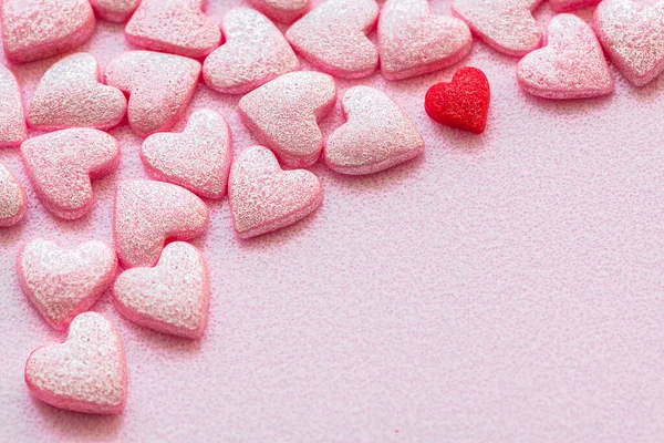Un montón de pequeños corazones rosados dulces y un corazón rojo en surfase rosa — Foto de Stock