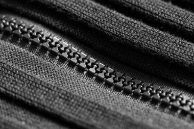 Siyah örgü kumaş üzerine siyah plastik fermuar. Kapatın. Makro.