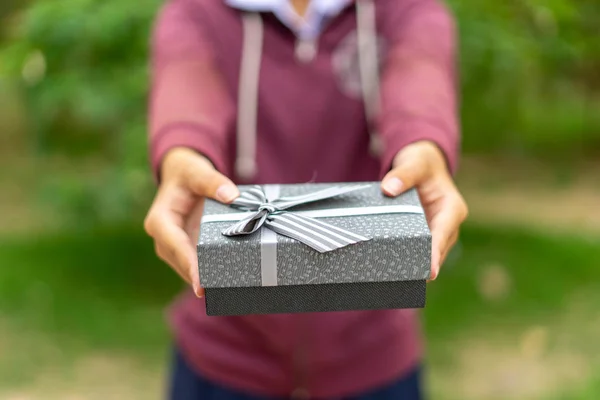 The girl's hand is giving a gift box for a special day or surpri