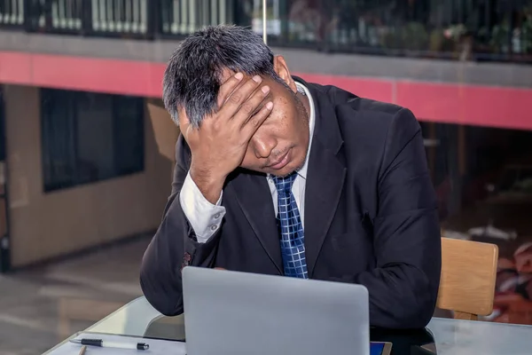 An Asian male businessman is sad and crying in front of the computer laptop for his failure management in finance business investigation work and job during a strong economic crisis issue