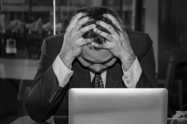 An Asian male businessman is sad and crying in front of the computer laptop for his failure management in finance business investigation work and job during a strong economic crisis issue