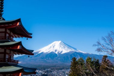Japonya 'nın Yamanashi ilindeki Arakurayama sengen parkından Fuji Dağı' nın kırmızı Chureito pagoda ve Fujiyoshida şehrinin ikonik görüntüsü..