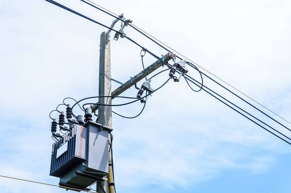 Electric transformer on electric pole with blue sky background.