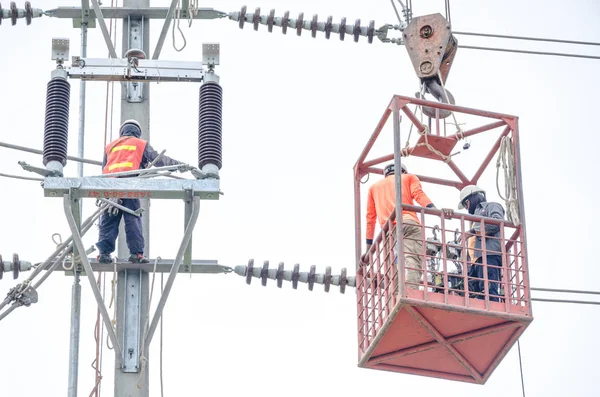 Electricians are climbing on electric poles to install and repair power lines.