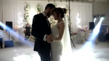 Evli çiftler düğünlerinde sahne ışıkları altında dans eder.