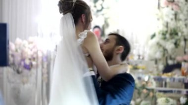 Damat gelinini kollarında tutuyor, düğün dekorasyonuna karşı dans ediyor.