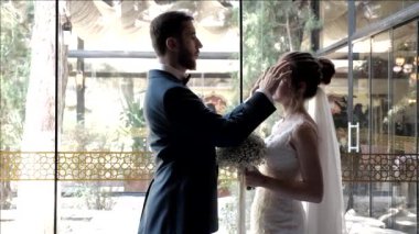 Damat gelinin yüzüne dokunur ve restoranda aşk pozu verir.