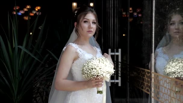 Вдумчивая невеста держит букет цветов, сверкающих под солнечными лучами — стоковое видео