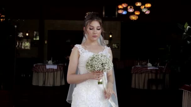 Bride holds bouquet with ribbons posing against restaurant — Stock Video