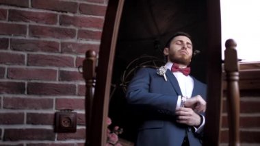 Damat düğmeyi bağlar ve tasmayı aynanın önünde ayarlar.