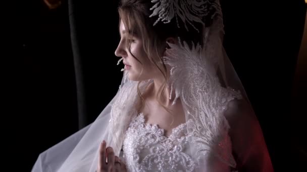 Bride in lacy corset holds veil and looks aside posing — Stock Video
