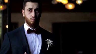 Gelinlik giymiş, papyonlu bir adam restoranda ağır çekimde.