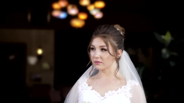 Bride in gorgeous dress holds bouquet in blurry hall slow — Stock Video