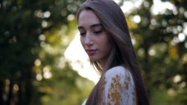 Kadın, gün ışığına ve ormana karşı poz veriyor.