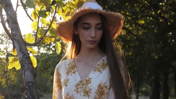 Jolie brune aux cheveux longs en chapeau de paille se tient dans le parc — Video