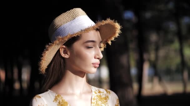 Leniwy brunetka lady w kapelusz przeciw zamazany park powolny ruch — Wideo stockowe