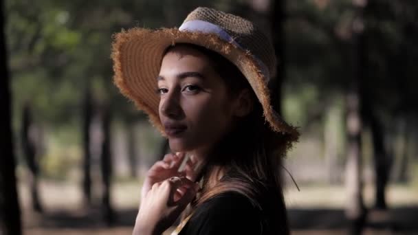 Mujer de pie media cara posando contra los árboles borrosos al atardecer — Vídeos de Stock