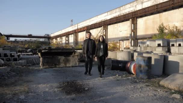 Couple walks along wasteland with old cement sewer rings — Stock Video