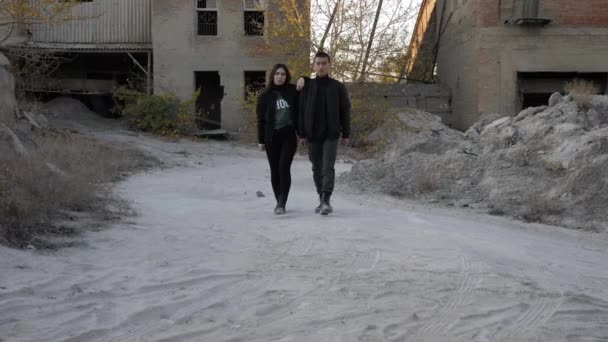 Junger Mann mit Freundin läuft auf schmutziger Straße in Zeitlupe — Stockvideo