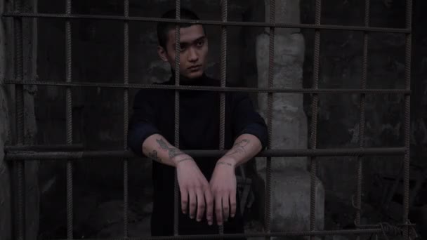 Young man in black leans on old rusty metal grid slow motion — Stock Video