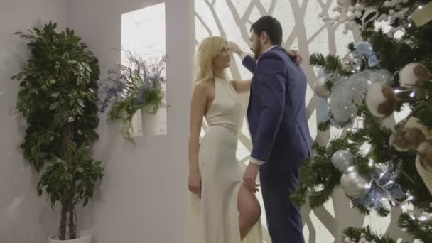 Чудова пара стоїть на білій дизайнерській стіні і спілкується — стокове відео