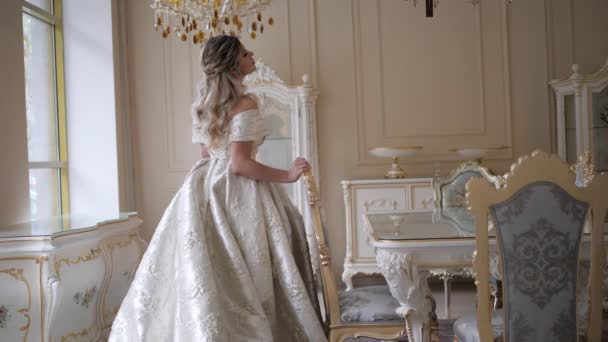 Bruid in taffeta jurk loopt in de kamer en gaat zitten op stoel — Stockvideo