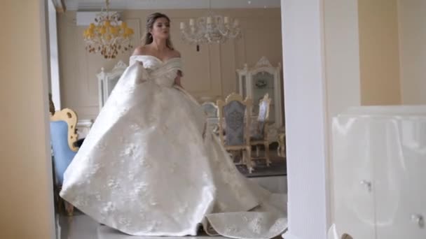 Mariée tourbillonne tenant robe blanche et pas le long de la chambre — Video