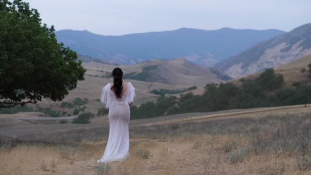 在高地，穿着露背衣服的女人沿着空旷的田野走着 — 图库视频影像