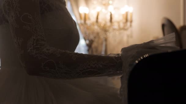 Novia en vestido precioso toca el piano en la habitación con velas — Vídeos de Stock