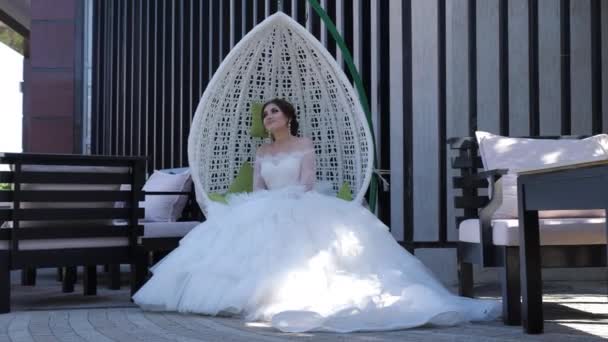 Jeune femme portant une robe de mariée repose dans une chaise suspendue — Video