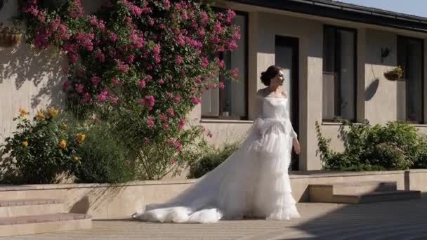 Senhora no vestido de casamento caminha por casa com rosas câmera lenta — Vídeo de Stock