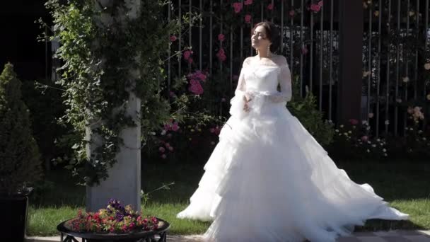 Mulher positiva no vestido de noiva perto de canteiro de flores câmera lenta — Vídeo de Stock