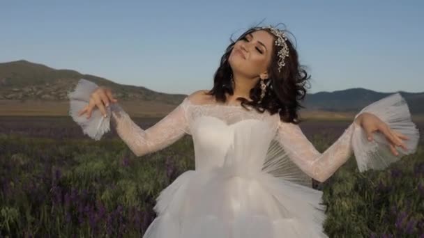 Девушка в свадебном платье с диадемой танцует в поле замедленной съемки — стоковое видео