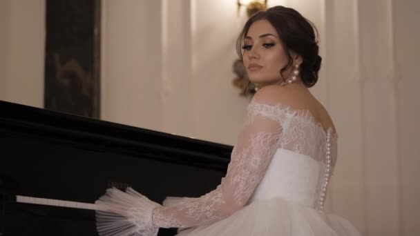 Chica bonita en vestido elegante toca el piano en la sala de bodas — Vídeos de Stock