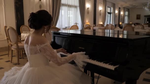 Brünette Braut im Spitzenkleid spielt im Restaurant-Saal Klavier — Stockvideo